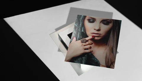 Composite photograph showing layered portrait prints arranged at angles on white paper with dramatic lighting.