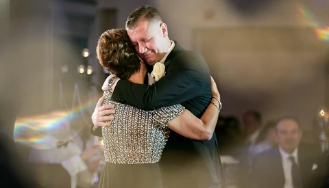 Couple embracing during a formal dance, with soft bokeh lighting and an indoor venue setting.
