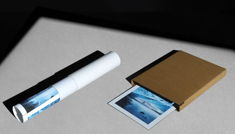 Product packaging mockups for photographic prints displayed on gray surface with dramatic side lighting.