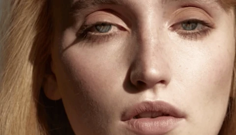 Close-up portrait of a woman with blonde hair and neutral expression, lit with soft, directional light creating subtle shadows.
