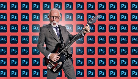 Professional man in business suit playing electric bass guitar against red and blue Adobe Photoshop logo background.