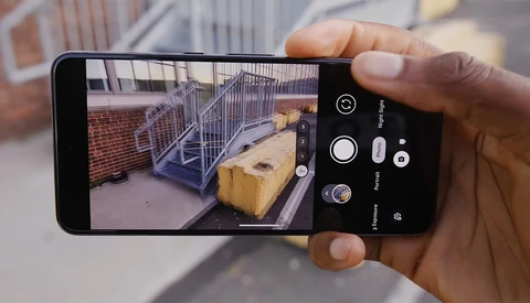 Smartphone camera app interface showing a construction site with metal railing and wooden boxes in the frame.