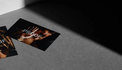 Two printed proofs with golden bokeh and warm lighting on a gray surface with dramatic shadow.