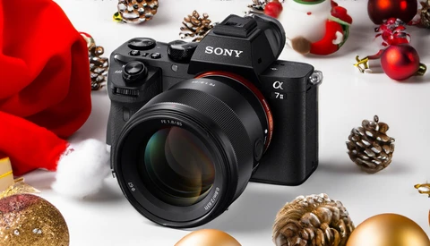 Sony mirrorless camera surrounded by festive Christmas ornaments and decorations on white surface.