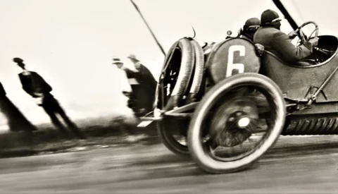 Vintage racing car number 6 captured in motion during early motorsport competition.
