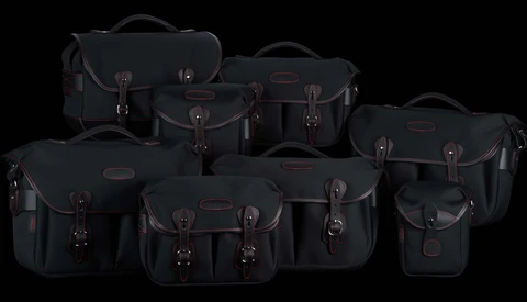 Collection of nine black camera bags and cases with brown leather accents arranged on a black background.