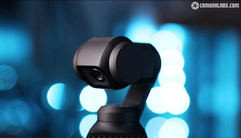 Three-axis gimbal stabilizer with mounted camera against blurred blue bokeh background.