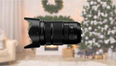 Black telephoto lens with lens hood against blurred holiday interior background.