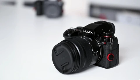 Panasonic Lumix mirrorless camera with attached prime lens on white surface.
