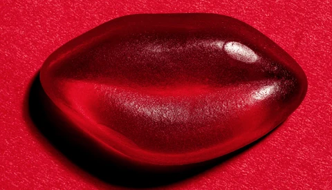 Deep red glossy three-dimensional shape against a bright red textured background with dramatic lighting.