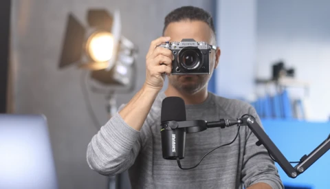 Photographer holding a vintage rangefinder camera in a studio with professional lighting setup.