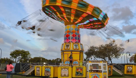 Colorful carousel ride with spinning swings in motion at an outdoor carnival or fair.
