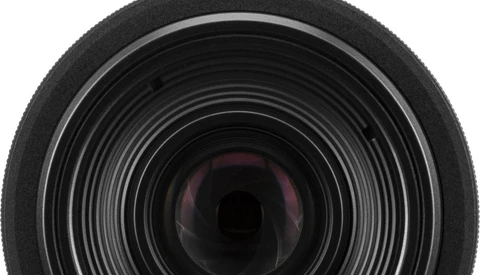 Close-up view of camera lens front element with concentric glass rings and internal reflections.