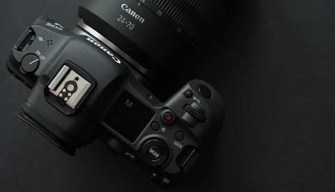 Canon EOS R5 mirrorless camera with Canon RF 70mm lens mounted, displayed on dark surface with top-down view.