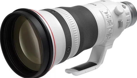 White telephoto lens with large front element and built-in tripod foot shown in profile view.