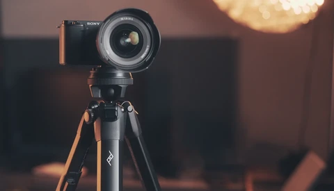 Sony mirrorless camera mounted on tripod with wide-angle lens, warm golden hour lighting in background.