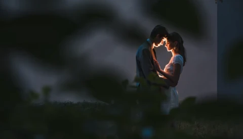 Couple embracing outdoors at dusk with warm backlighting creating a glowing silhouette effect.