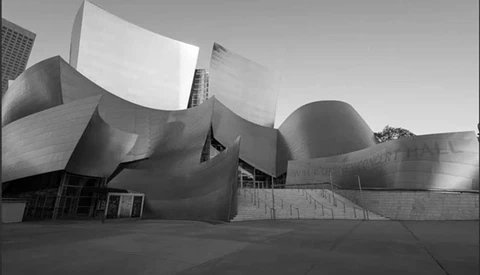 Black and white photograph of a modern curved architectural building with flowing metallic surfaces and angular geometric forms.
