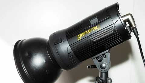 Generau studio flash with reflector mounted on stand against white background.