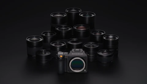 Medium format camera body surrounded by approximately 14 black prime lenses arranged in a pyramid formation.