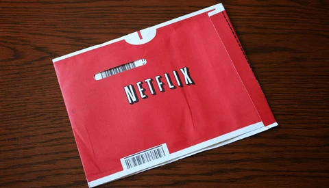 Red Netflix DVD envelope with white logo and barcode labels on wooden surface.