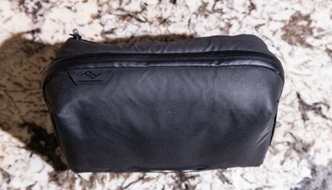 Black nylon toiletry bag with zipper closure on textured granite surface.