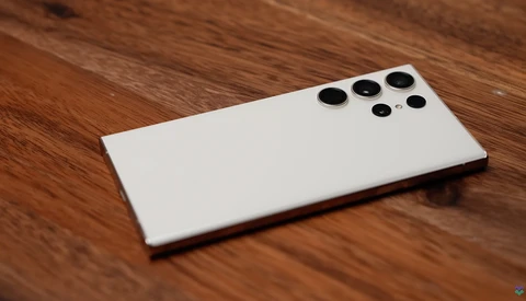 White smartphone with quad rear camera module on wooden surface.