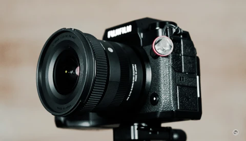 Fujifilm medium format film camera with wide-angle lens mounted on tripod against neutral background.