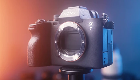 Sony a7 mirrorless camera body displayed against warm orange and cool blue gradient lighting.