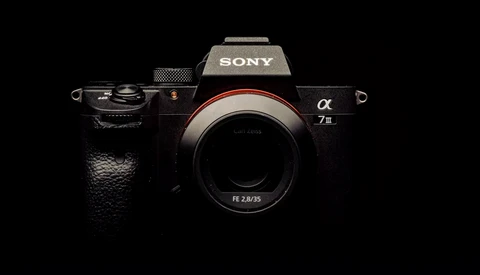 Sony a7 III mirrorless camera body with FE 2.8/35 lens mounted, photographed against black background.
