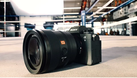 Sony α9 mirrorless camera with G-series lens on concrete surface in modern building.