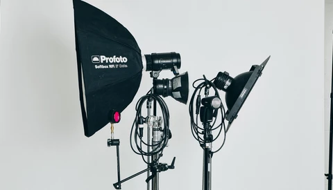 Three professional studio lighting fixtures mounted on stands against a white backdrop.