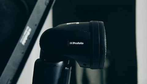 Profoto studio flash head mounted on a light stand against a dark background.
