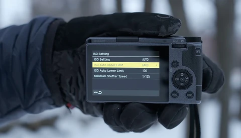 Camera LCD screen displaying ISO settings menu with AUTO mode selected and lower limit set to 100.