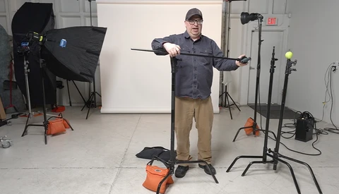 Photographer demonstrating lighting technique with reflector in professional studio setup.