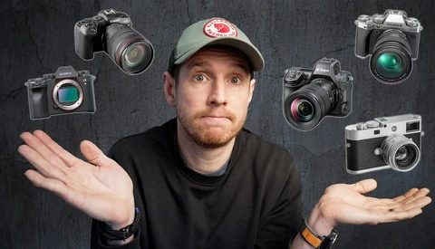 Photographer wearing cap with hands gesturing uncertainty, surrounded by six different camera models floating around him.
