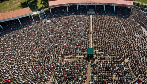 Aerial view of a massive crowd filling a stadium field during an organized event or gathering.