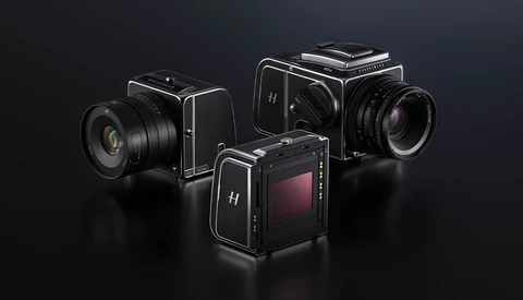Three medium format film cameras with interchangeable lenses arranged on a dark surface.