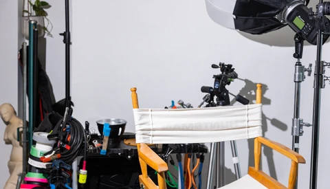 Photography studio setup with lighting equipment, reflectors, and production gear arranged on tables.