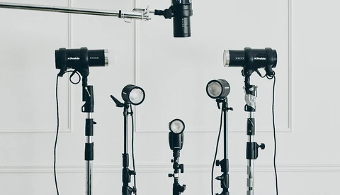 Professional studio lighting setup with five mounted light fixtures and overhead rigging against white walls.