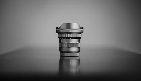 Wide-angle lens with prominent front element and focus ring, photographed against neutral background.