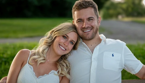 Couple posing together outdoors on a lawn, smiling at camera in natural daylight.