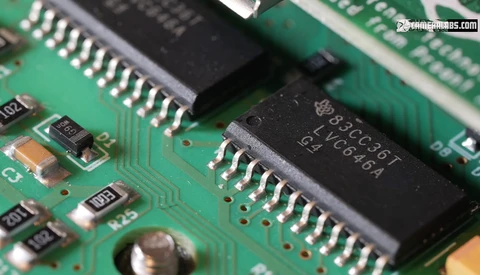 Close-up of integrated circuit chips on a green circuit board with visible component markings and solder joints.