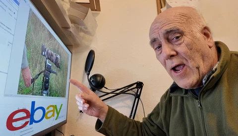 Man pointing at computer monitor displaying eBay logo and aerial property photograph.