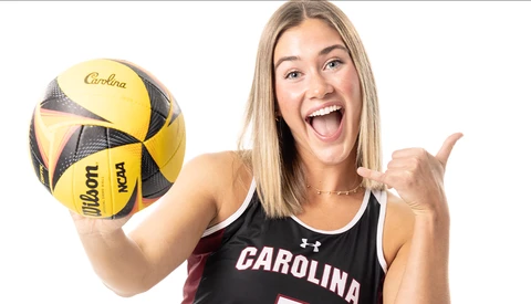Athlete in Carolina tank top holding yellow and black volleyball while giving thumbs up.