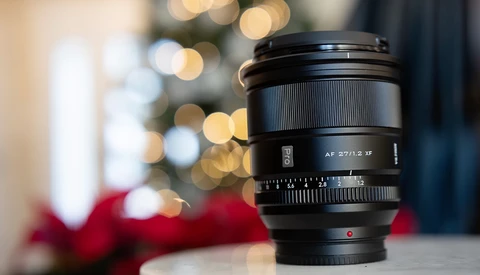Sony AF 27/2.8 manual focus lens positioned in front of blurred holiday bokeh background.