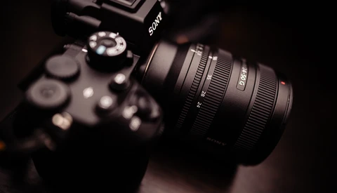 Sony mirrorless camera with attached zoom lens on dark background.