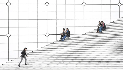 People scattered across a monumental staircase, some climbing, others sitting and socializing on the steps.