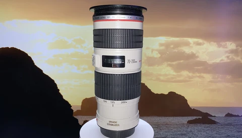 Canon EF 70-200mm f/2.8L telephoto lens displayed against a coastal sunset with rocky islands.