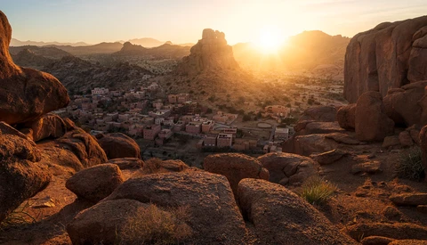 Desert town nestled among granite rock formations at golden hour sunset.